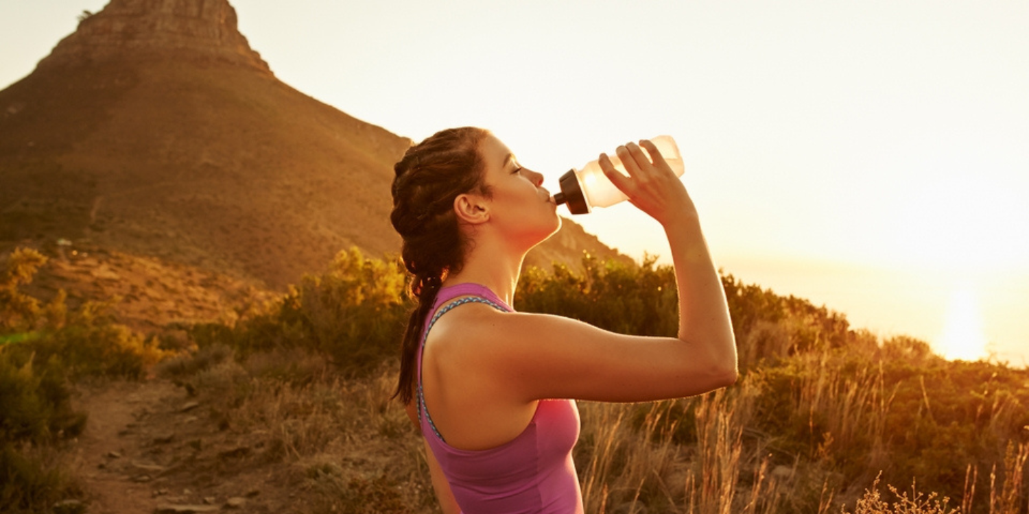showing the importance of hydration: a woman drinking water in the outdoors